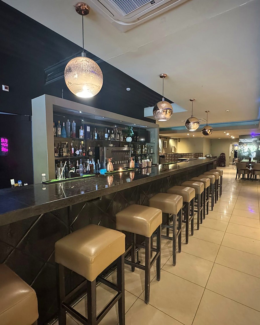The long bar with leather stools and backlit bottles